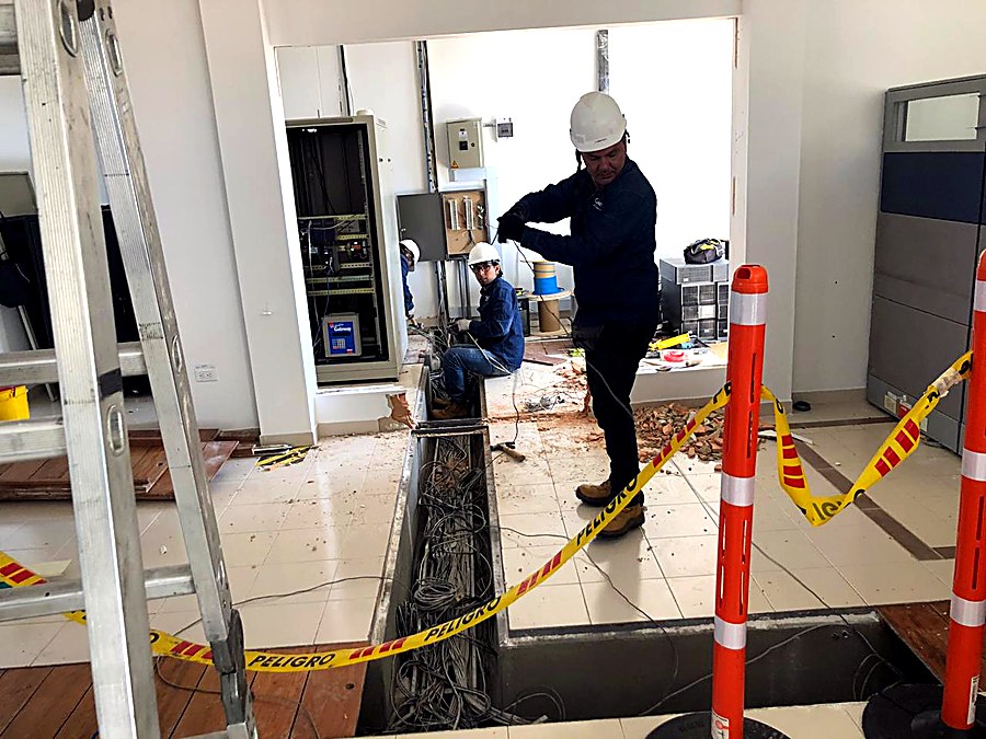 Técnicos de Cybertec instalando cableado estructurado bajo piso técnico